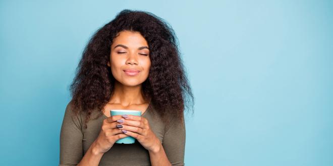 a woman with a calmly glowing smile holding a mug of tea