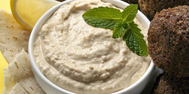 a bowl of creamy hummus and some falafel