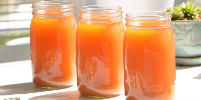 Three mason jars filled with homemade detox broth on a table in the sunlight.