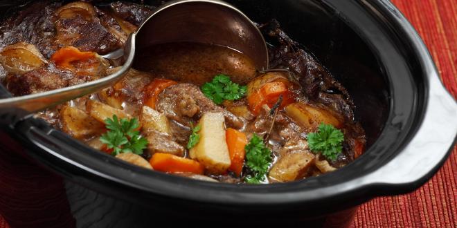 A pot full of hearty beef stew with carrots and potatoes.